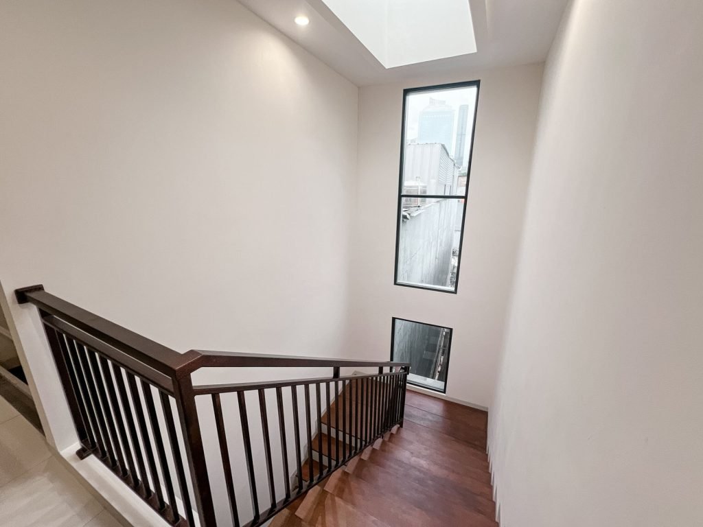 The internal staircase at Arcelon Premiere with a timber handrail and a tall window