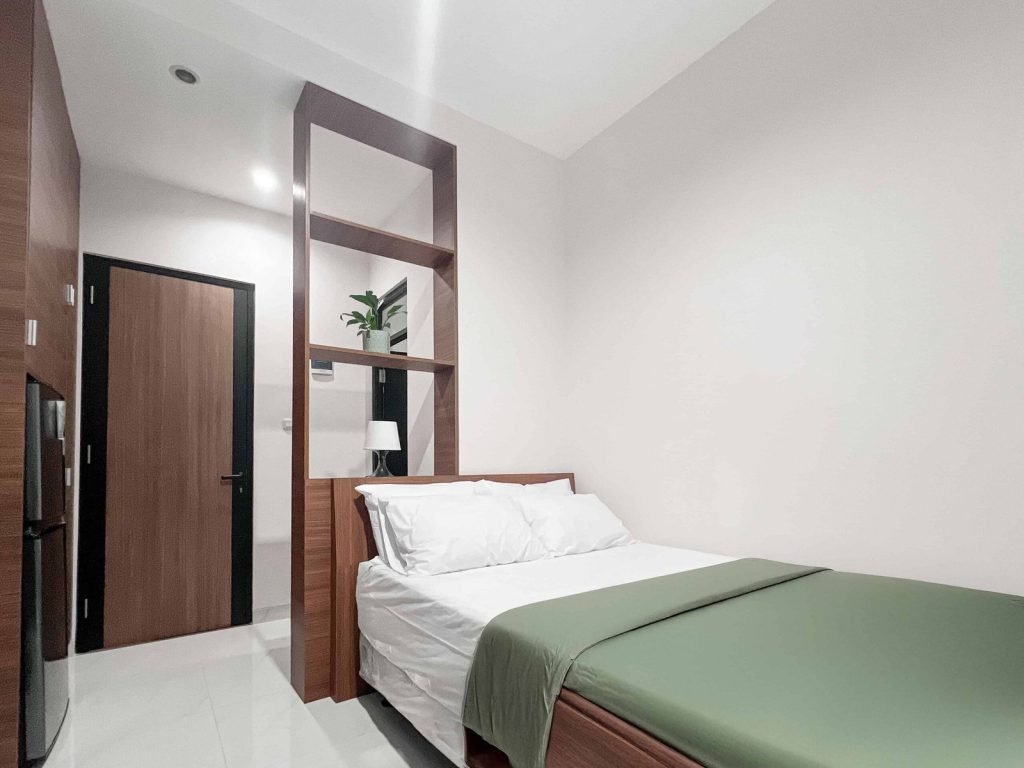 A Deluxe room at Arcelon Premiere with a double bed, refrigerator and timber joinery