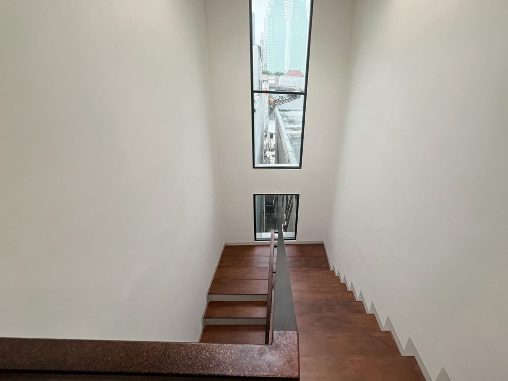 A tall stairwell at Arcelon Premiere lit by narrow windows