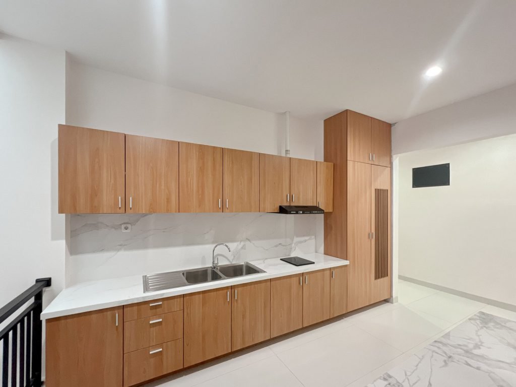 The communal kitchen at Arcelon Premiere with timber cabinets, a sink and a hob