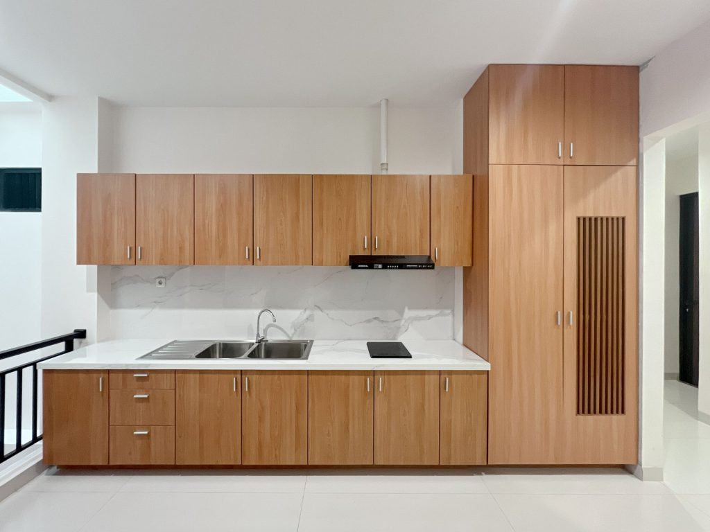 The communal kitchen at Arcelon Premiere with timber cabinets, a sink and an induction hob
