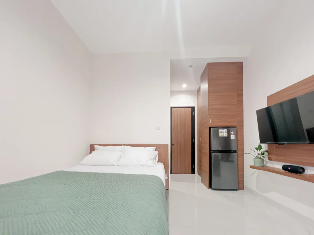 A Deluxe room at Arcelon Premiere with a double bed, refrigerator and wall-mounted television