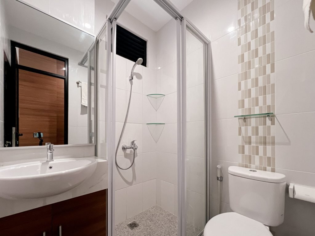 A private bathroom at Arcelon Premiere with a glass shower enclosure, washbowl and toilet