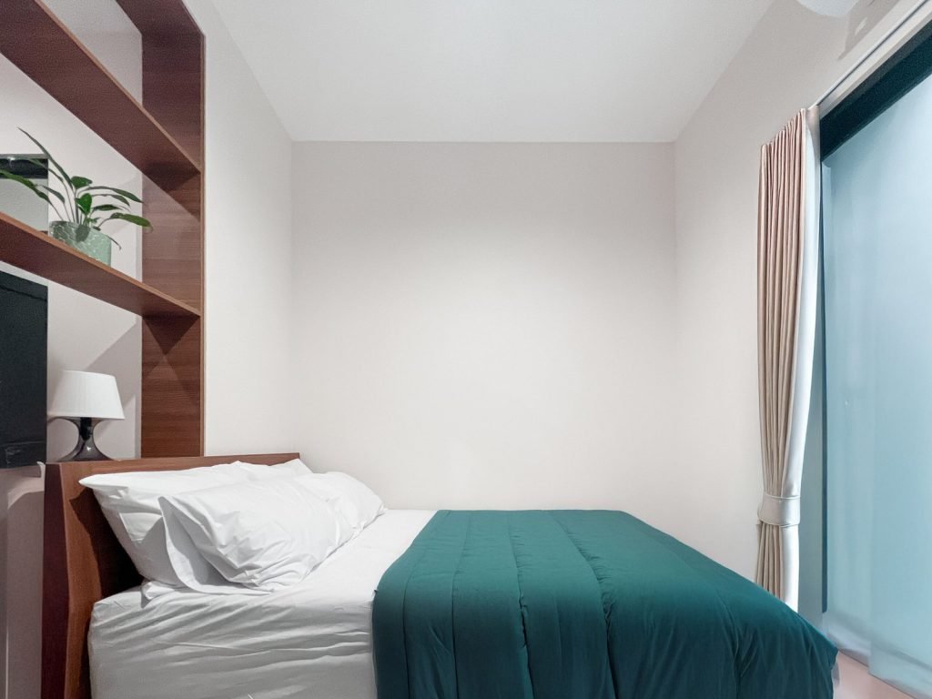 A bed and timber shelving beside the window in a room at Arcelon Premiere