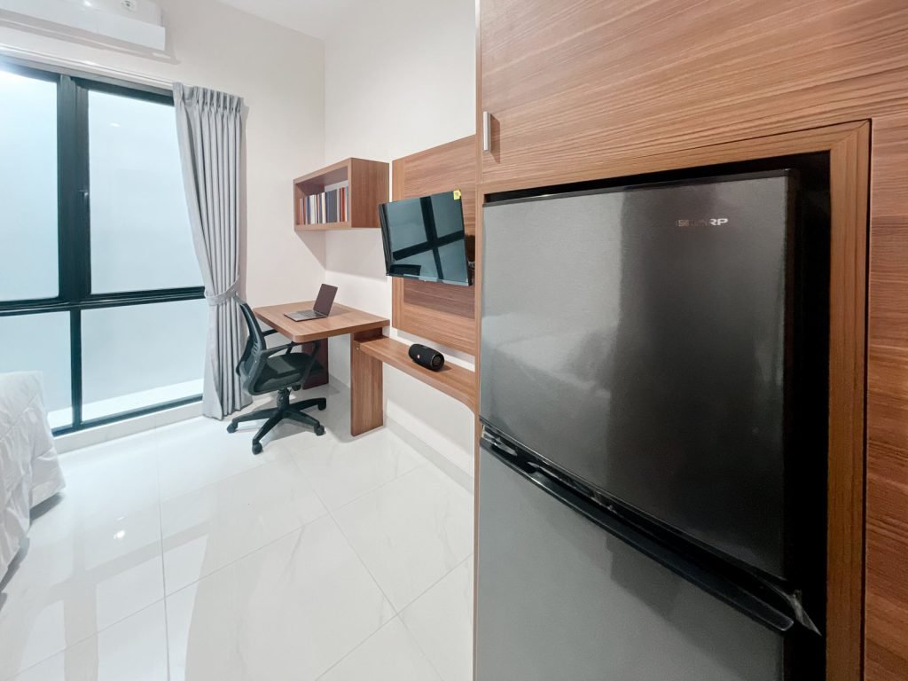 A room at Arcelon Premiere with a refrigerator, television, work desk and window