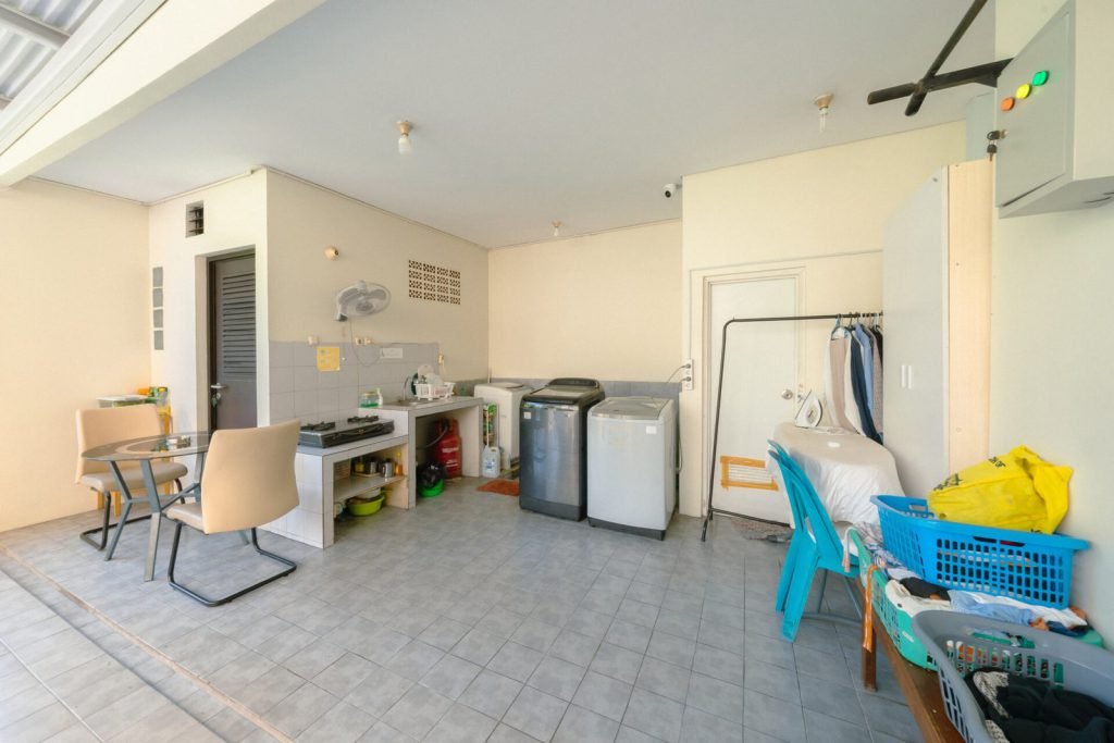 The shared utility room at Arcelon Executive with washing machines and an ironing station
