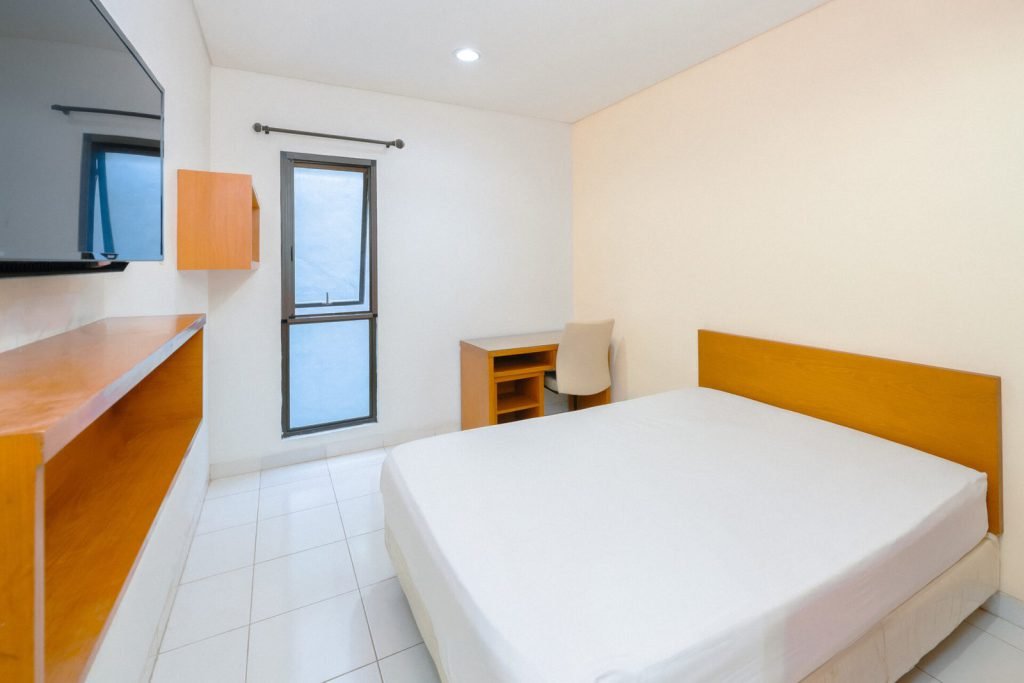 A Deluxe room at Arcelon Executive with a double bed, timber shelving and a window