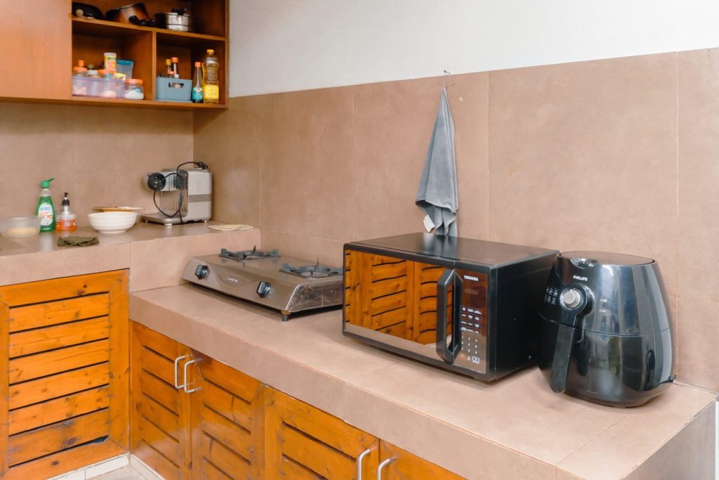 The communal kitchen at Arcelon Stay Karawaci with a hob, microwave and air fryer