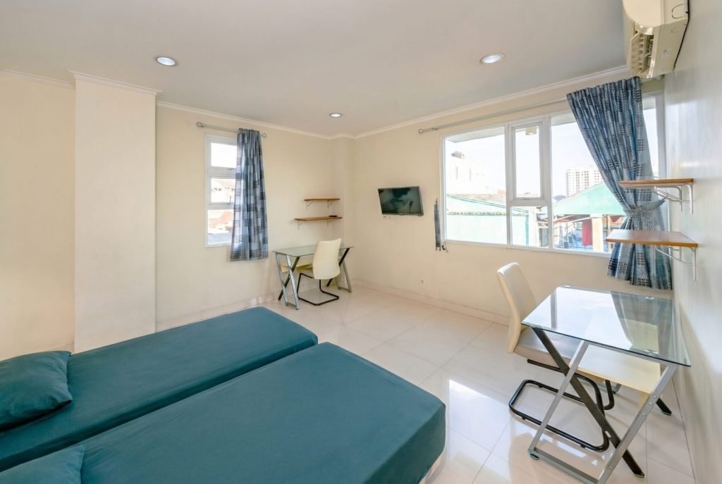 A furnished room at Arcelon Stay Karawaci with a bed, glass desk and curtained window
