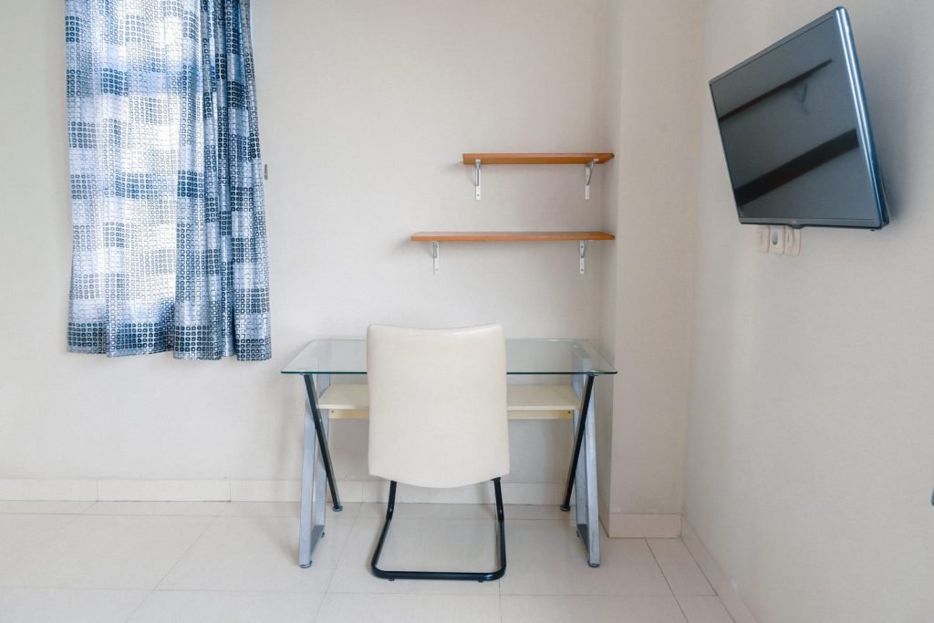 The work desk, wall shelves and television in a room at Arcelon Stay Karawaci
