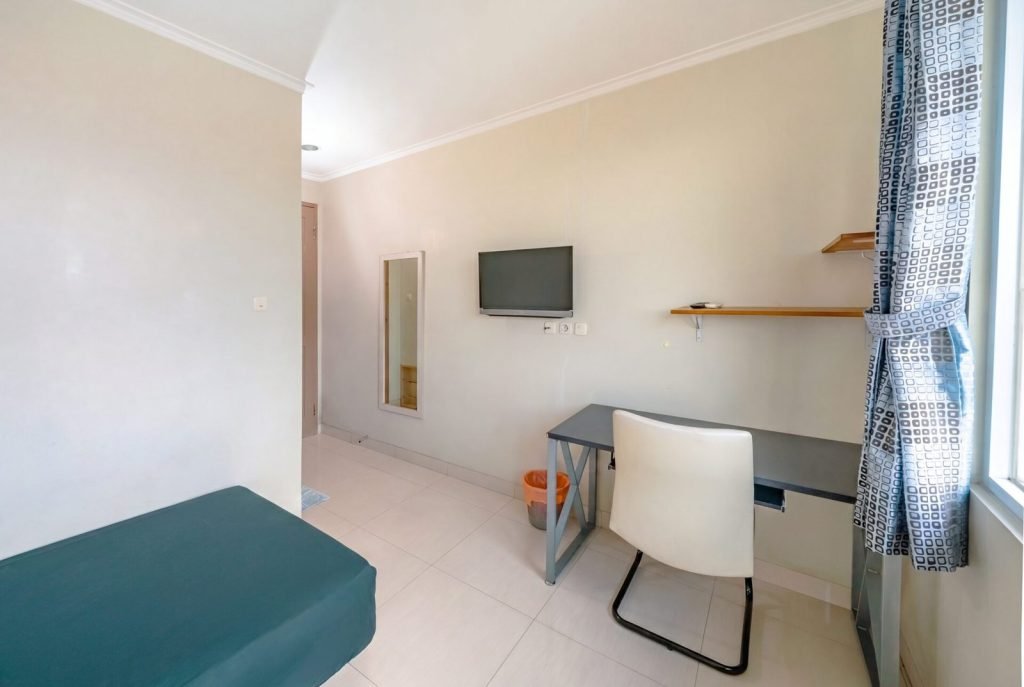 A room at Arcelon Stay Karawaci with a television, work desk, office chair and curtained window