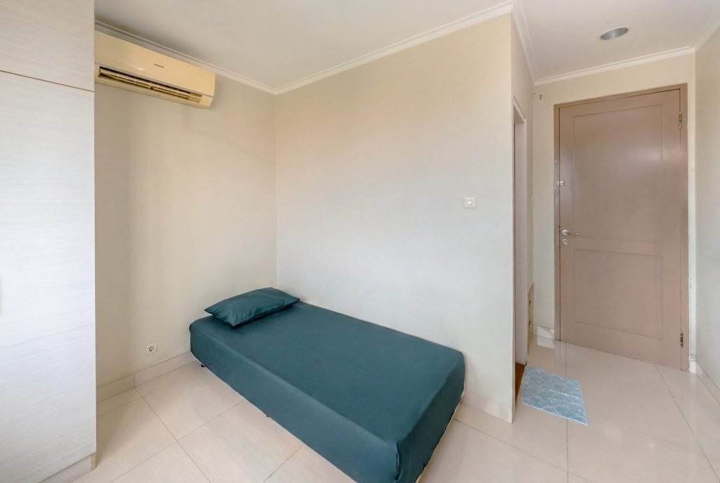 A single bed and air conditioning unit in a room at Arcelon Stay Karawaci