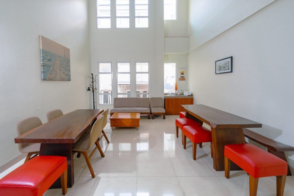 The communal dining area at Arcelon Stay Karawaci with long timber tables and red benches