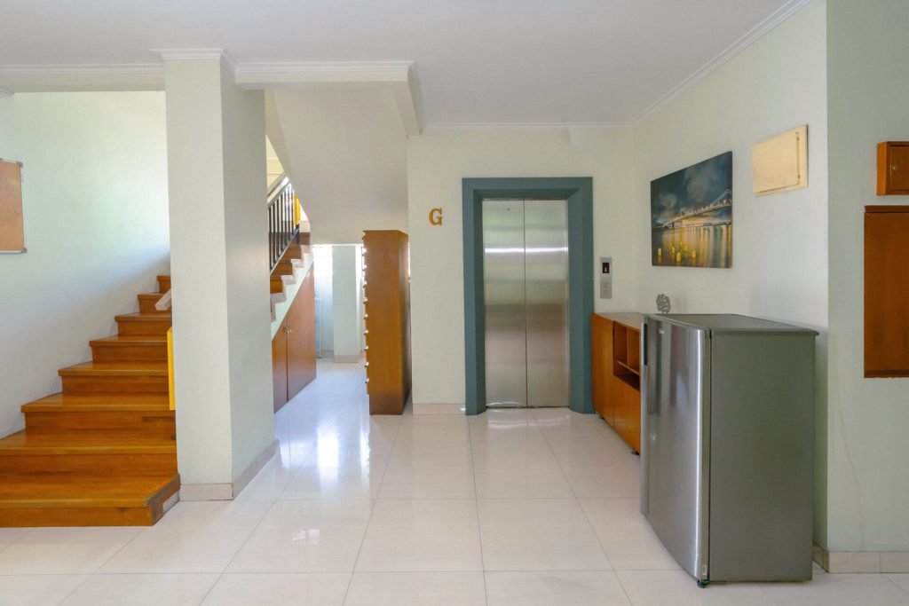 The ground-floor lobby at Arcelon Stay Karawaci with a staircase, lift and shared refrigerator