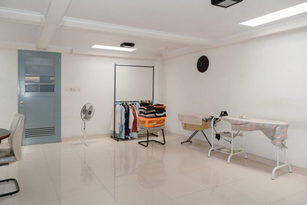 The shared ironing and drying room at Arcelon Stay Karawaci with clothes rails and ironing boards