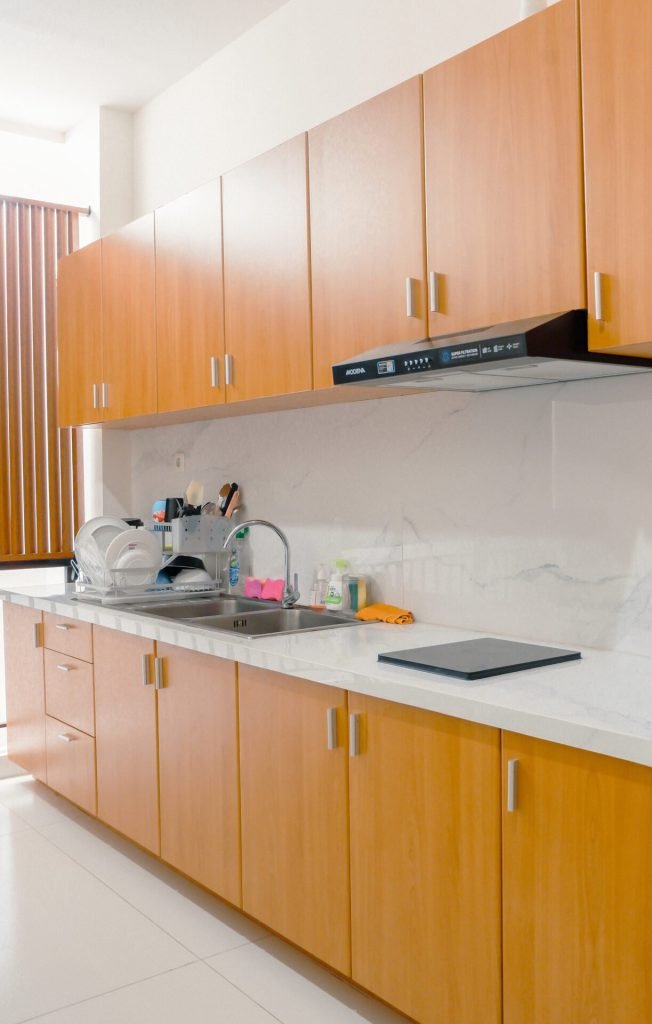 The pantry counter at Arcelon Premiere with timber cabinets, a sink and a kettle