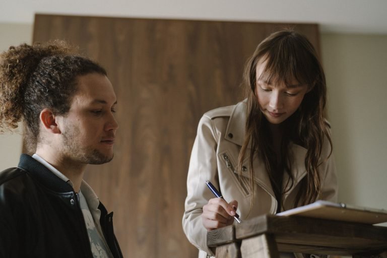 Two people reading and signing tenancy documents at a table
