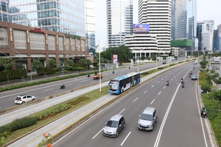 A main road in central Jakarta with buses, cars and office towers
