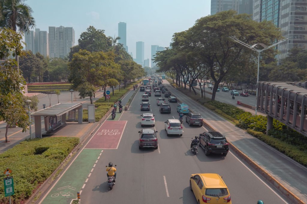 A busy Jakarta roadway with cars, motorbikes and a bus stop