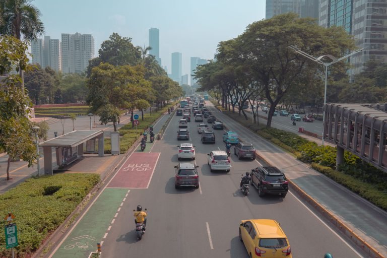 A busy Jakarta roadway with cars, motorbikes and a bus stop