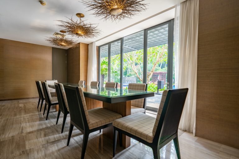 Meeting room with a long glass-topped table, upholstered chairs and gold starburst pendant lights, overlooking the garden