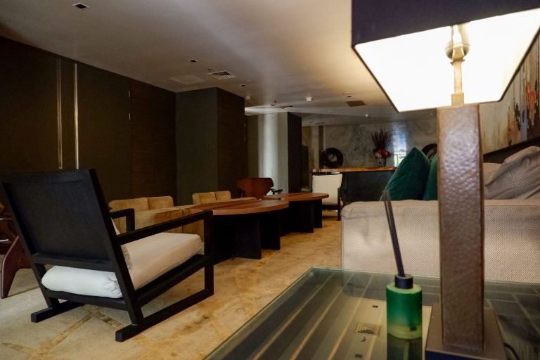 Lounge seating beside a shared work table, with a floor lamp and pool table in the foreground