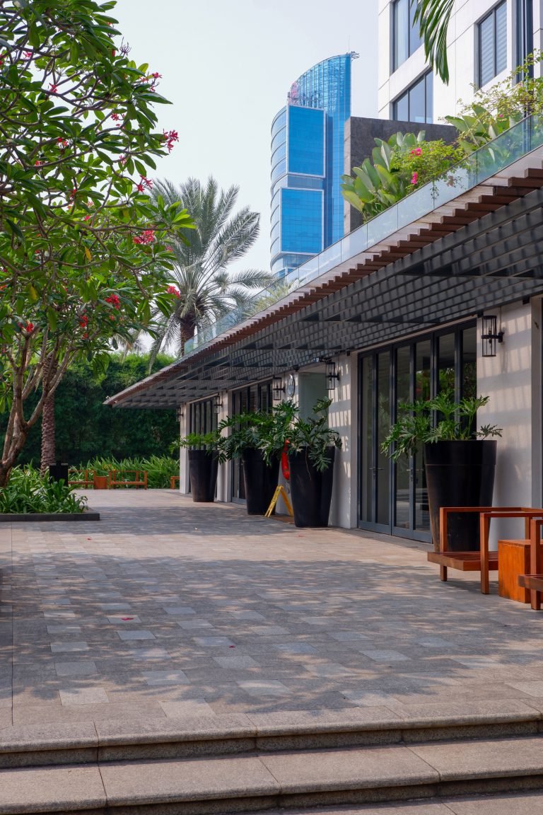Paved terrace outside the pavilion, with planters and seating along the wall