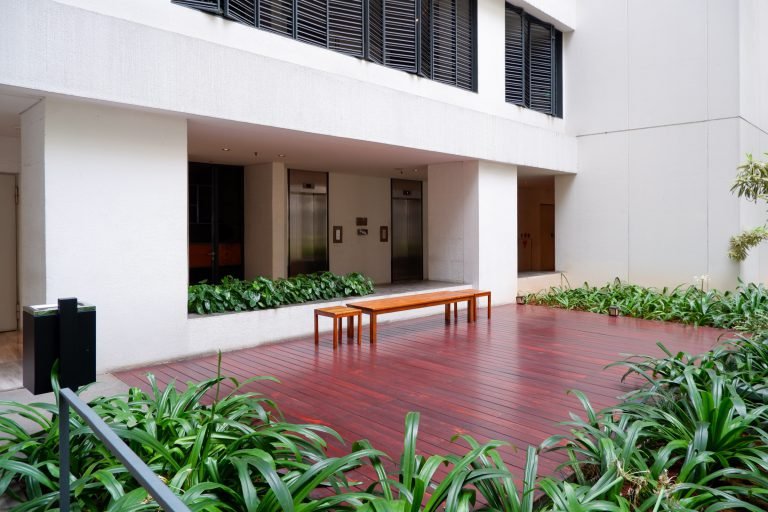 Covered walkway beside the building with a timber bench and planting bed alongside