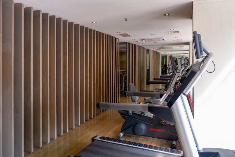 Cardio area with treadmills along a slatted timber feature wall and mirrored panels opposite