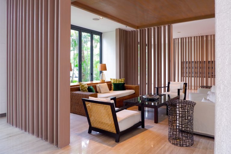 Lounge with rattan armchairs and a sofa beside timber screening, opening onto the garden