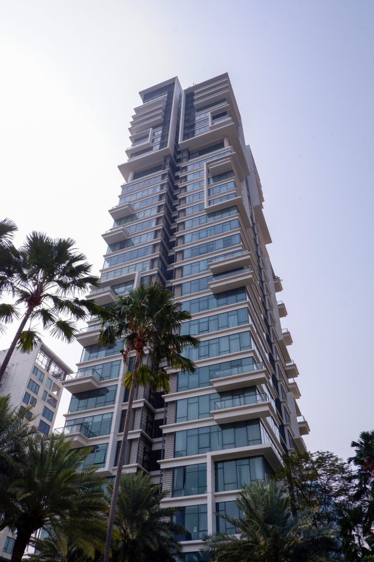 Residential tower viewed from below, palm fronds in the foreground against the sky