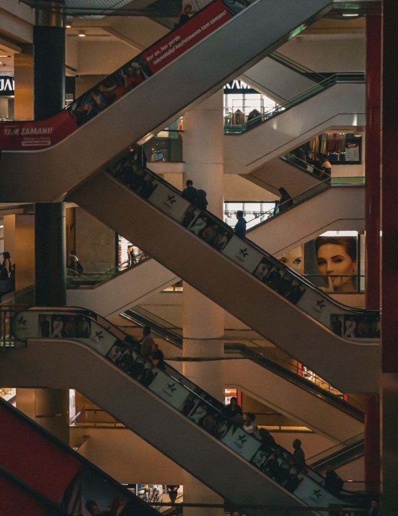 A multi-level shopping mall interior with escalators and shoppers