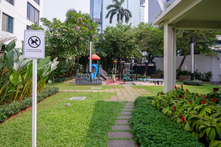 Landscaped garden path leading to the children's playground, with a lawn and shrub borders