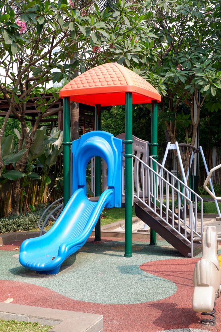 Play tower with a blue slide and steps, set on red rubber safety matting
