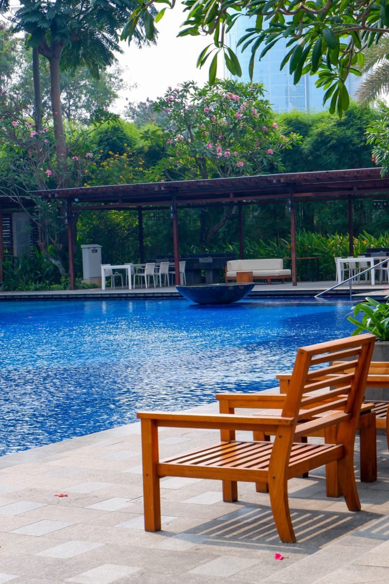 Timber bench beside the pool deck, shaded by mature trees