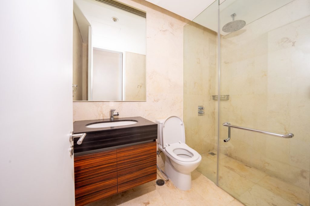 Guest bathroom in cream marble with a walk-in rain shower, dark wood vanity and wall-mounted mirror