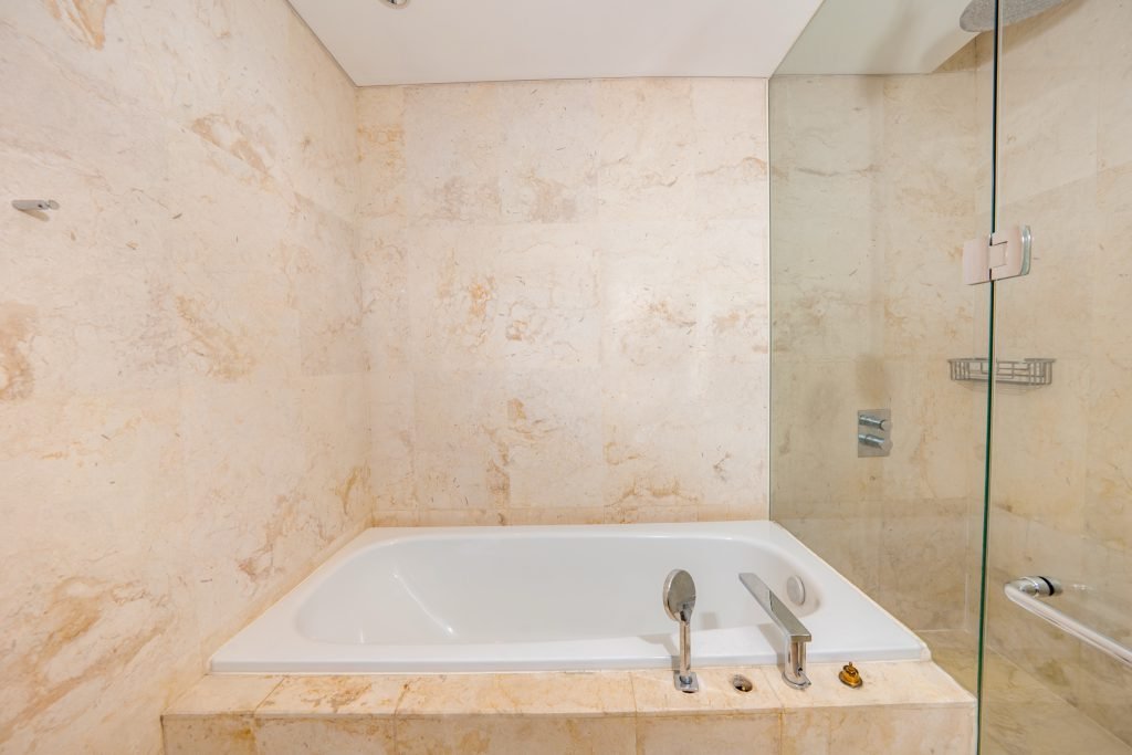 Marble bathroom with a built-in soaking bathtub set beside a glass shower enclosure