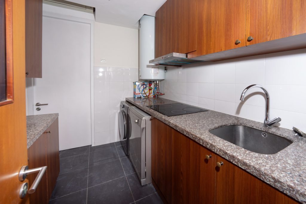 Kitchen with granite worktop, undermount sink, dark tiled floor and timber overhead cabinetry