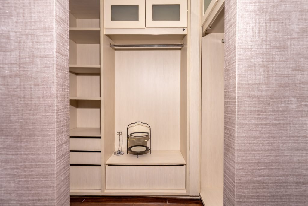 Walk-in wardrobe with open hanging rails, drawers and shelving in pale timber