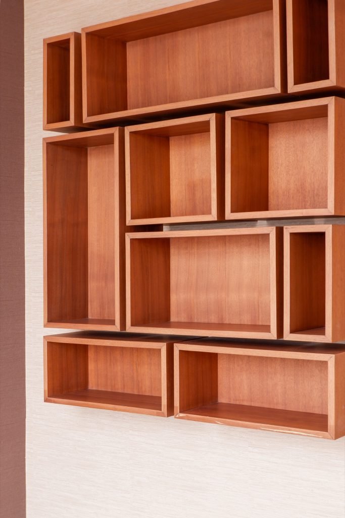Geometric timber display shelf with open compartments mounted on the bedroom wall