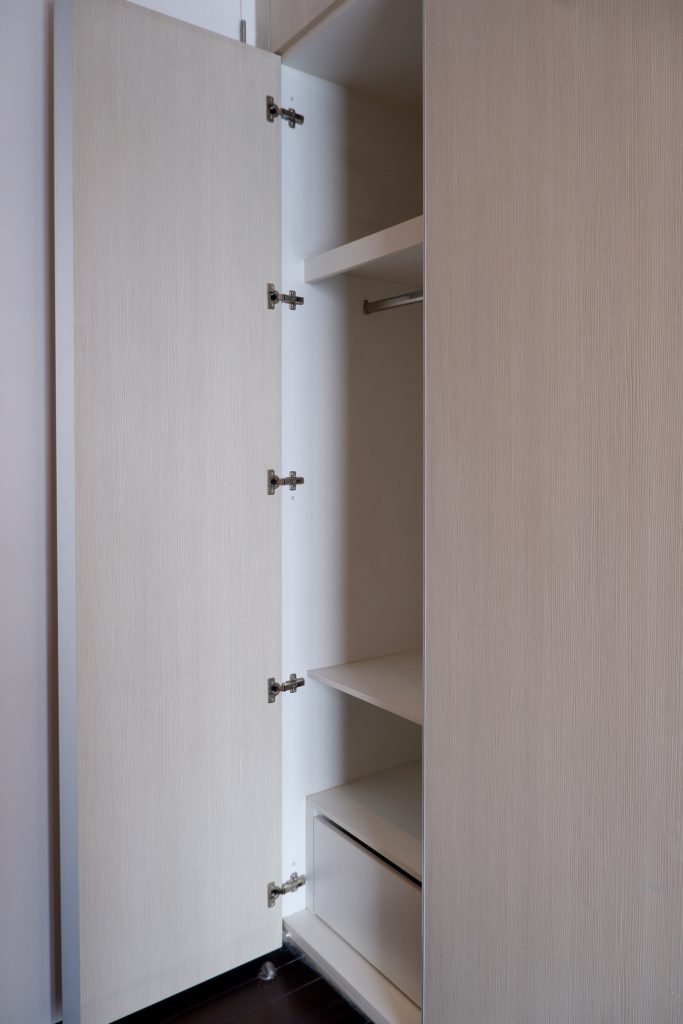 Fitted white wardrobe with open door showing internal shelving