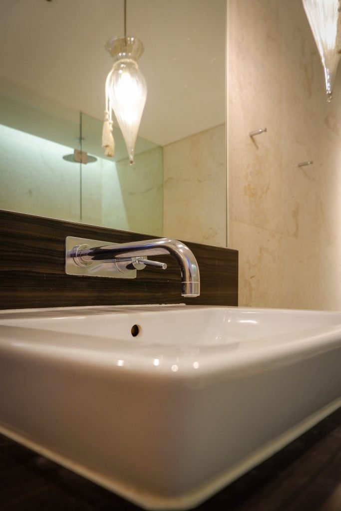 Bathtub with recessed lighting and a marble surround