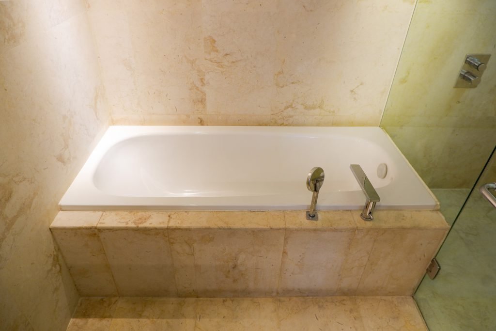 Built-in bathtub in cream marble with wall-mounted tap fittings