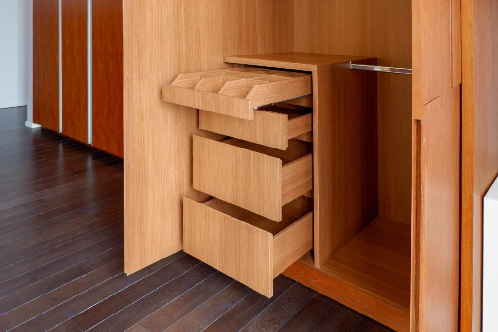 Wardrobe with pull-out timber drawers open, dark timber flooring below