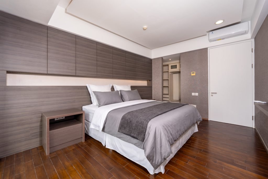 Bedroom with a dark timber feature wall, grey and white bedding and built-in bedside ledges