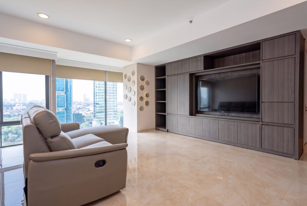 Living room with a reclining sofa, built-in timber media wall and windows onto the city skyline