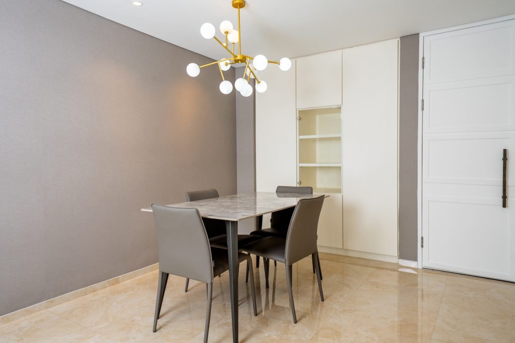 Dining area with a four-seat table, pendant chandelier and built-in white shelving