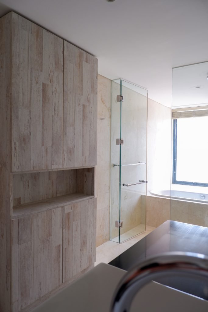 Bathroom detail with timber cabinetry and a mirrored wall beside the basin