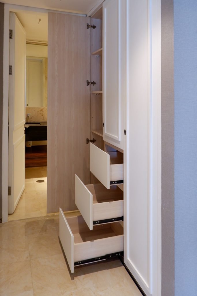 Wardrobe with pull-out drawers open, viewed through the doorway into the bedroom
