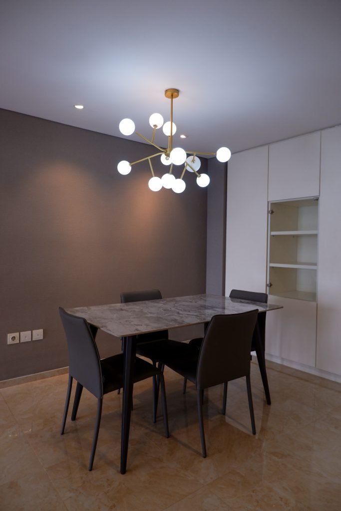 Dining table for four beneath a cluster pendant light, beside built-in white joinery